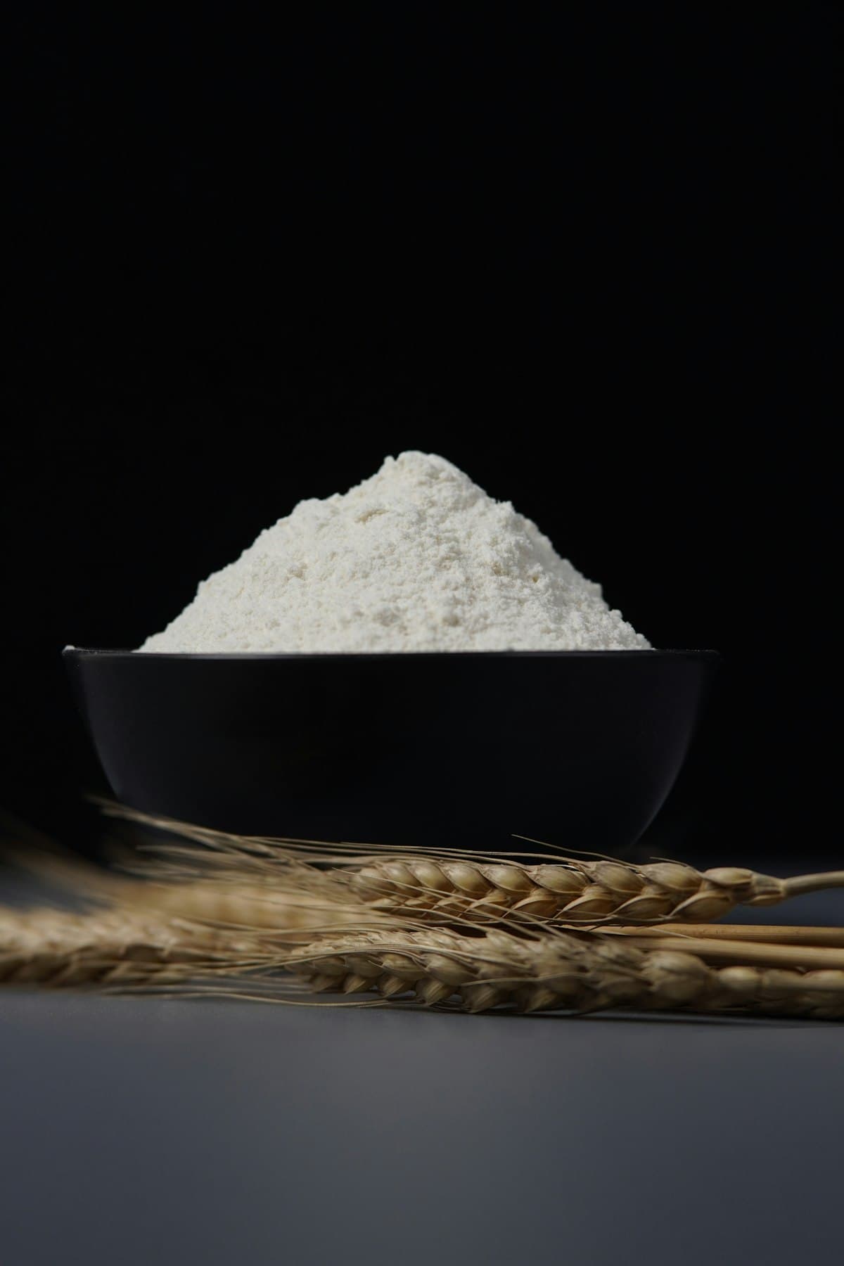 A bowl of freshly milled flour beside ears of wheat