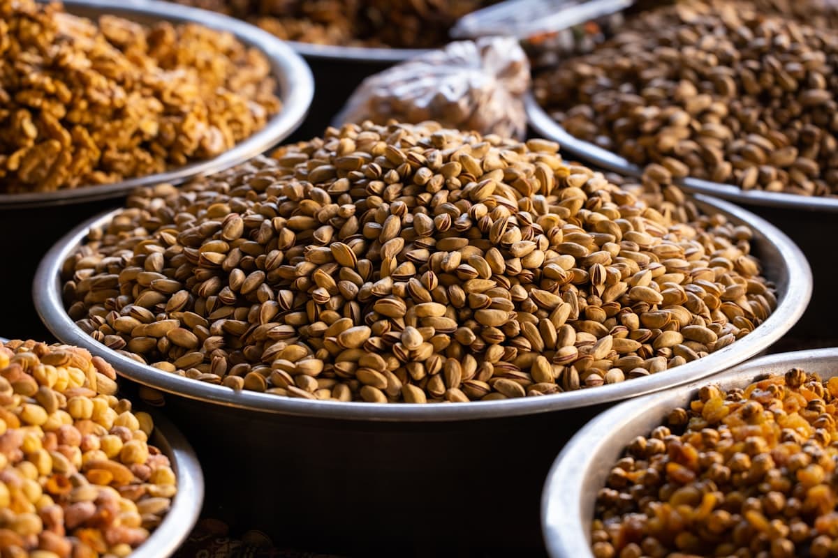 Metal bowls of pistachios, walnuts, raisins and other dry fruits at a market